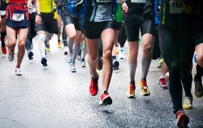 Recovery after running a marathon - Image of the lower half of runners during a marathon. They are running towards the camera