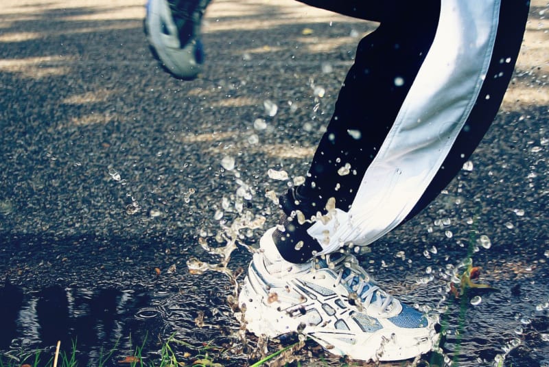 cold-weather-knee-pain-close-up-of-a-man-running-through-a-puddle